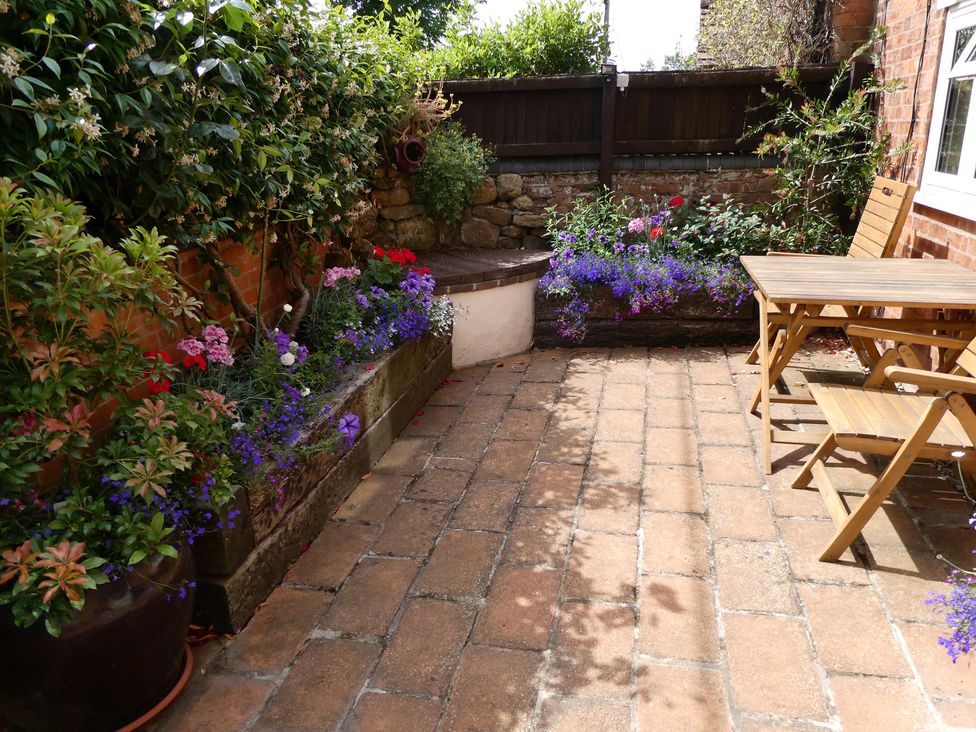 A garden with flowers and a table with chairs at Evas Cottage in Southam
