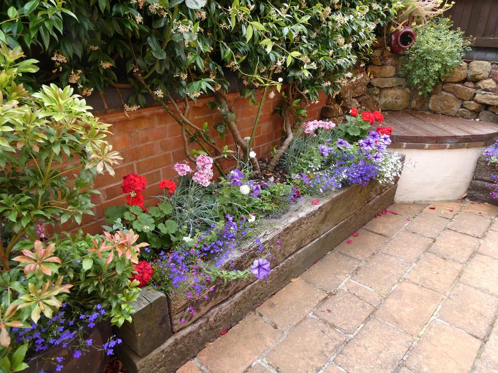 A garden with a planting bed and flowers at Evas Cottage in Southam