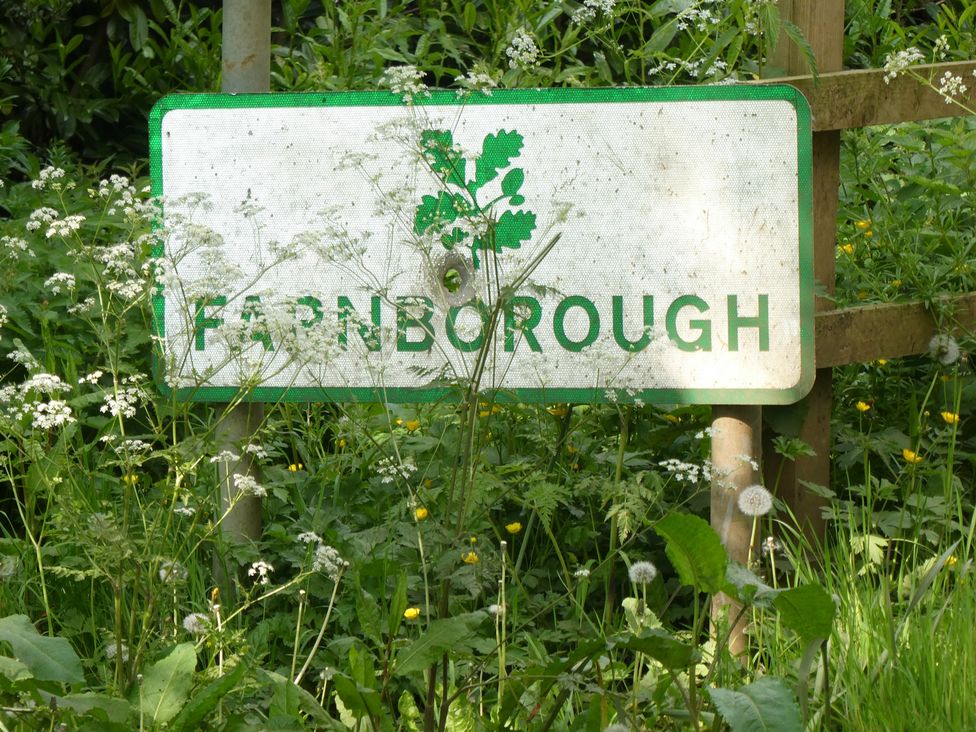 A sign indicating Farnborough surrounded by grass and wildflowers at Evas Cottage Southam