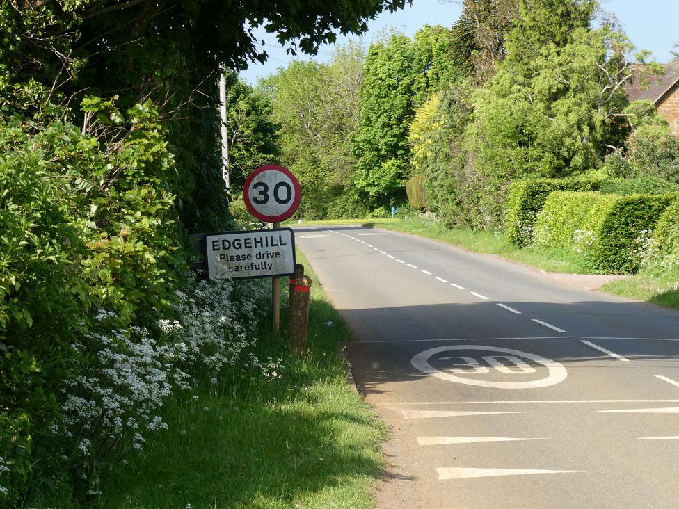 A road with a speed limit sign and village sign at Edgehill