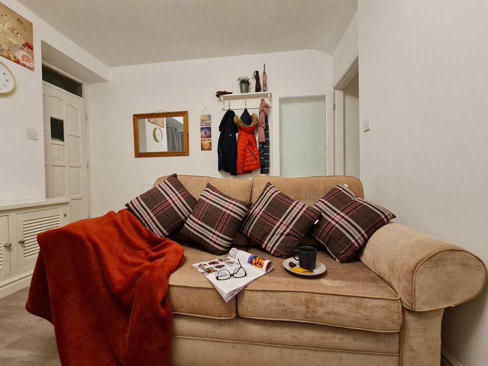 A living room with a sofa and a coat rack at Blue Haven in Penmaenmawr