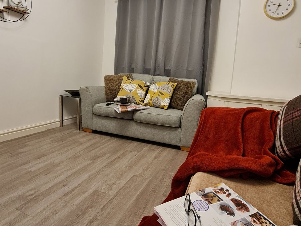 A living room with a sofa and cushions at Blue Haven in Penmaenmawr