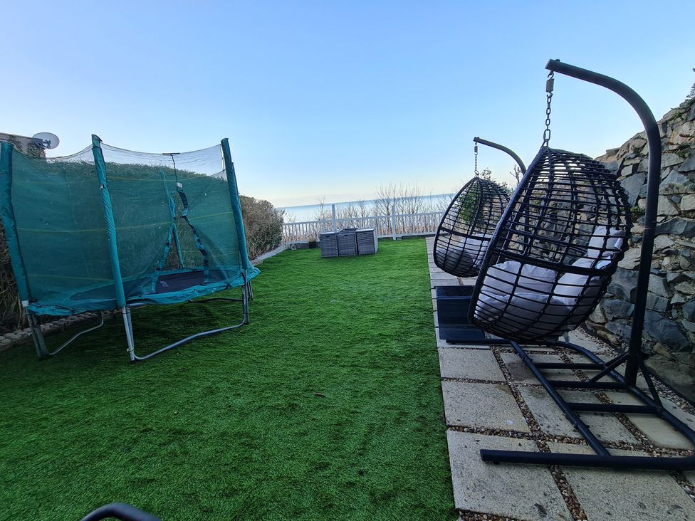 A garden with a trampoline and hanging chairs at Blue Haven in Penmaenmawr