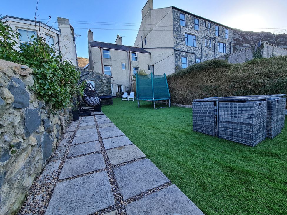 A garden with artificial grass and a stone pathway at Blue Haven in Penmaenmawr