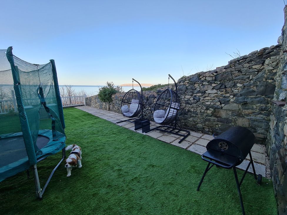 An outdoor area with a trampoline and hanging chairs at Blue Haven in Penmaenmawr