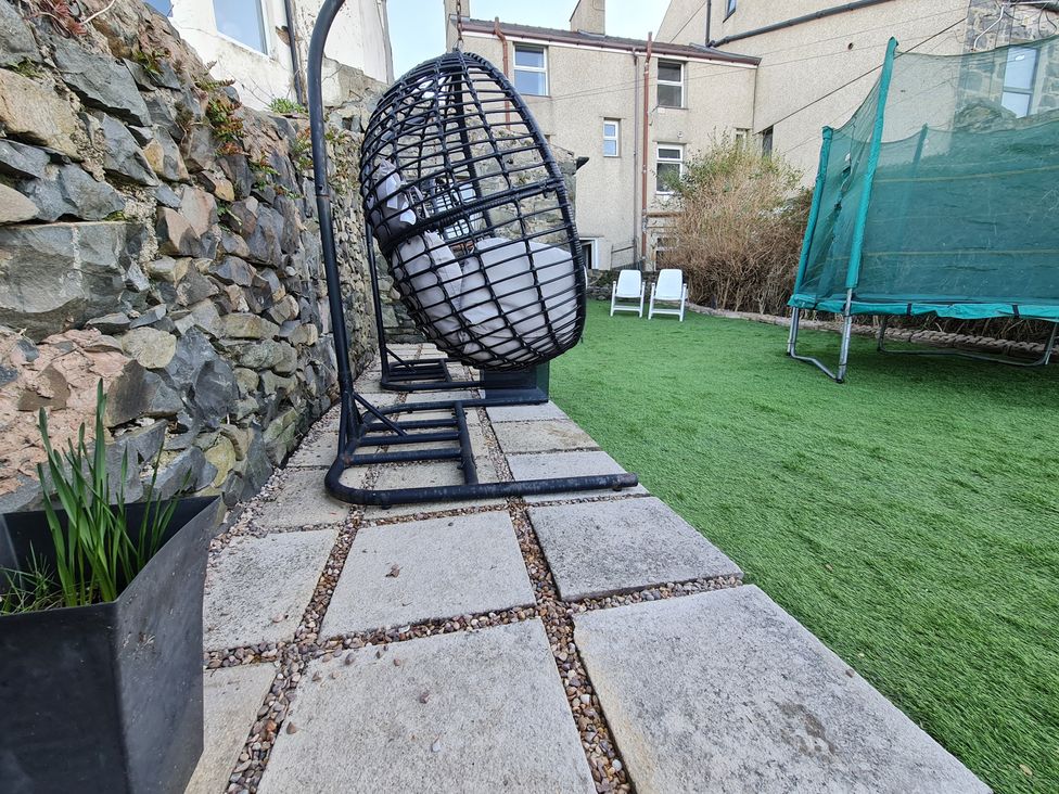 A garden with a hanging chair and trampoline at Blue Haven in Penmaenmawr