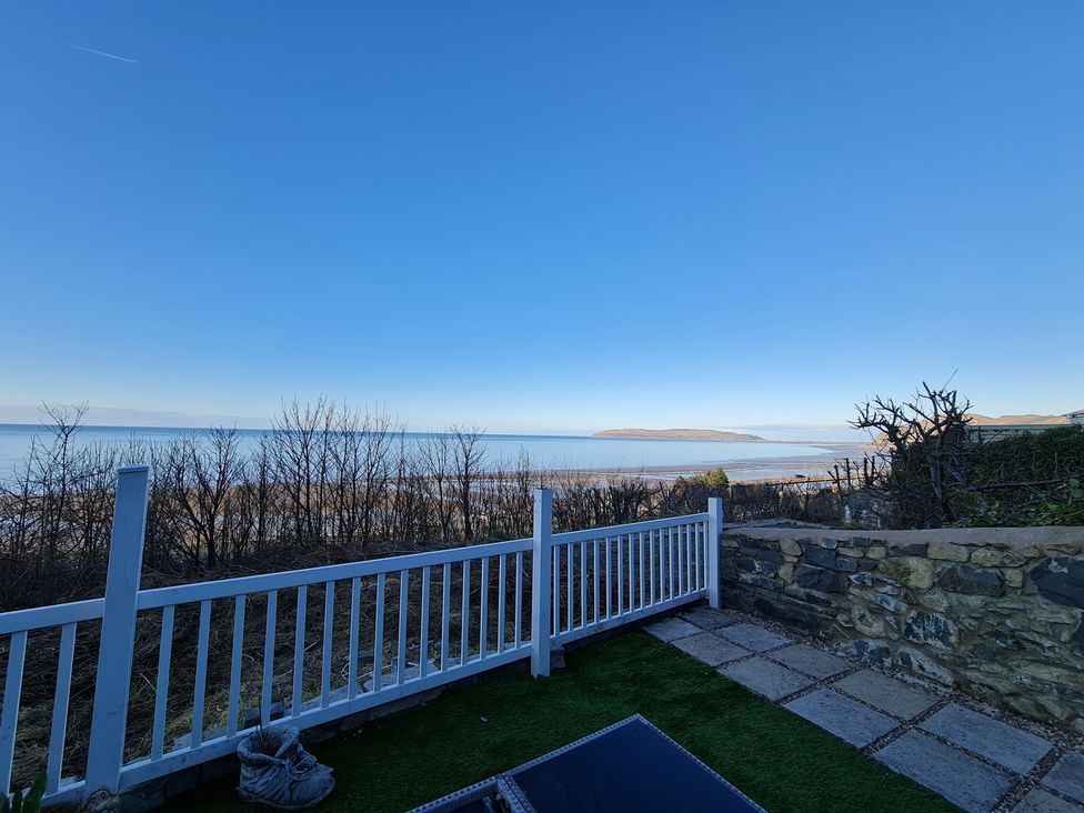 A view of the sea and shore from a fenced area at Blue Haven in Penmaenmawr