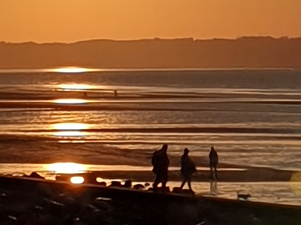 People walking on the beach during sunset at Blue Haven Penmaenmawr