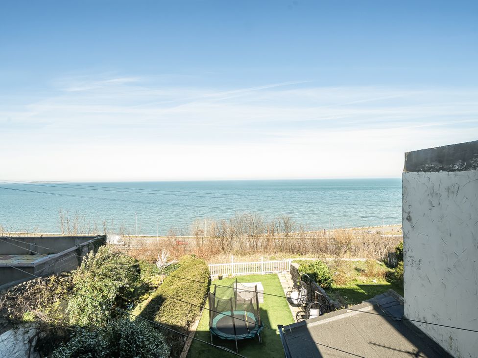 A view of the sea and garden with a trampoline at Blue Haven in Penmaenmawr