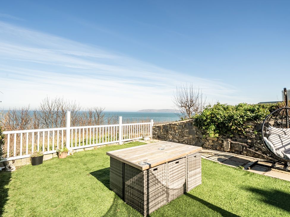 A garden with a table and chairs overlooking the sea at Blue Haven in Penmaenmawr