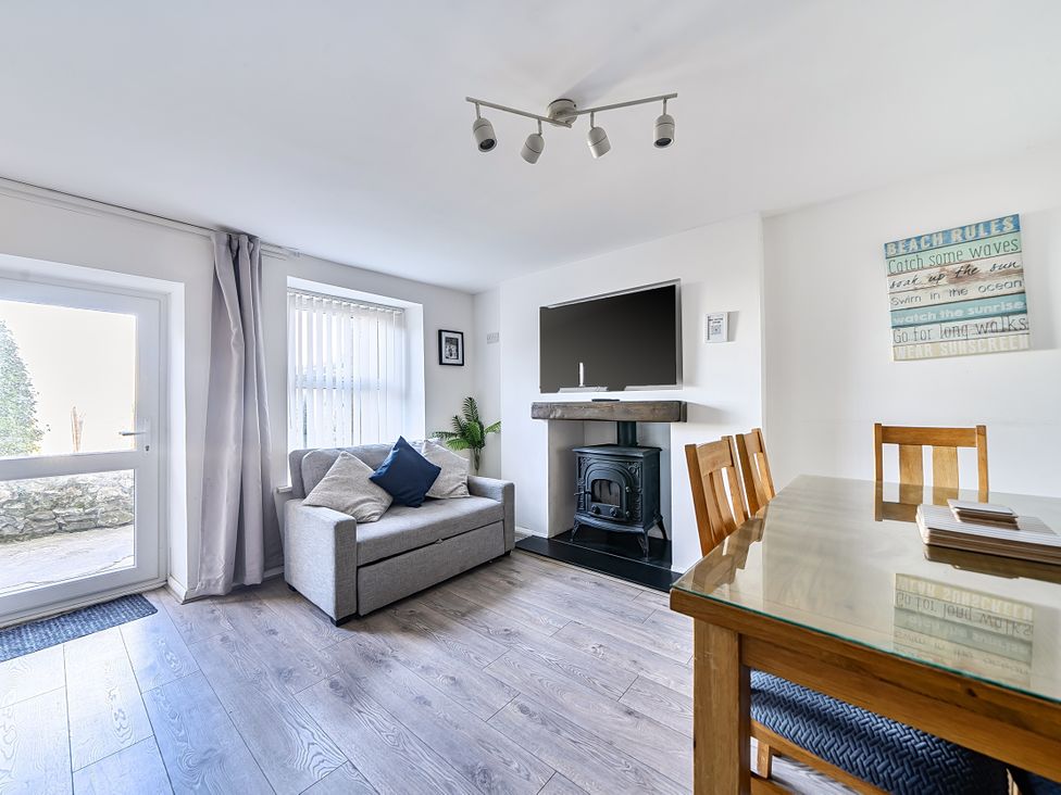 A living room with a sofa and dining table at Blue Haven in Penmaenmawr