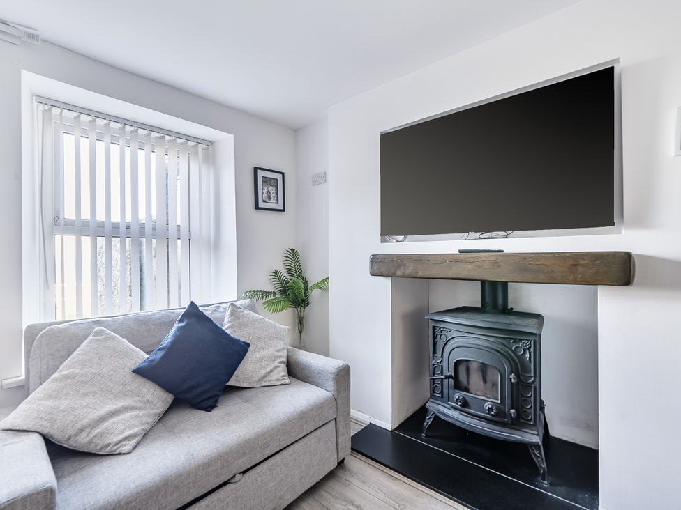 A living room with a sofa, television, and fireplace at Blue Haven in Penmaenmawr
