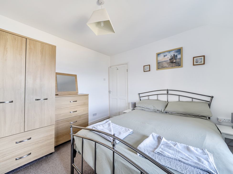 A bedroom with a bed, wardrobe, and drawers at Blue Haven in Penmaenmawr