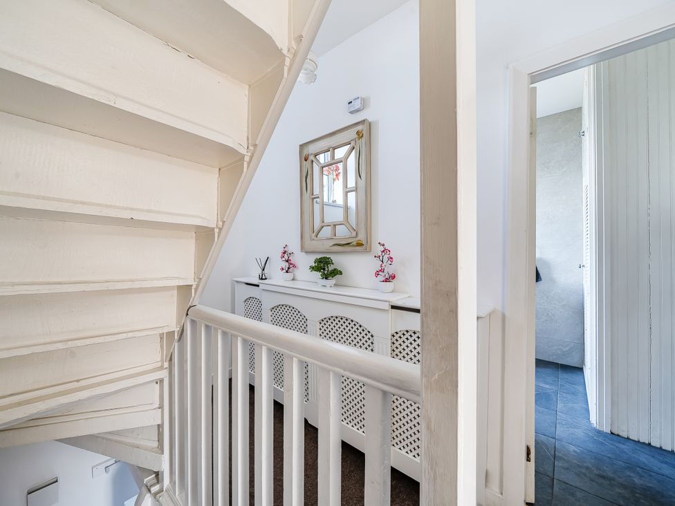 A hallway with a staircase and a console table at Blue Haven in Penmaenmawr