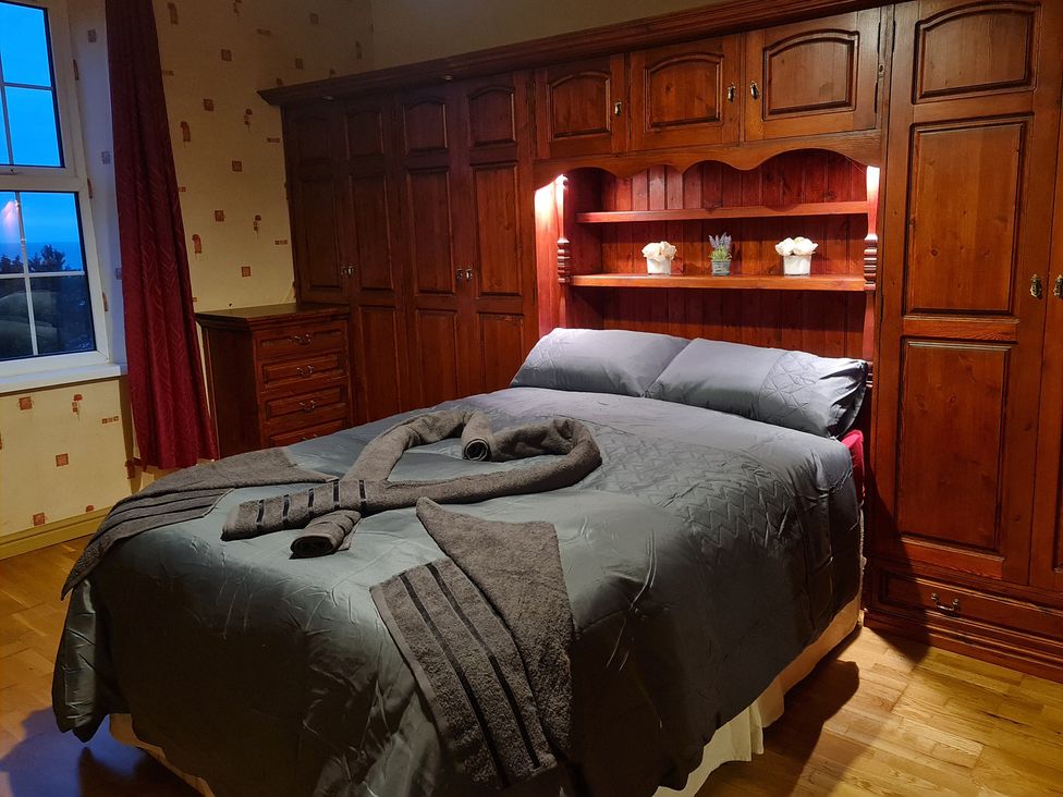 A bedroom with a bed and wooden furniture at Sea View Escape in Penmaenmawr