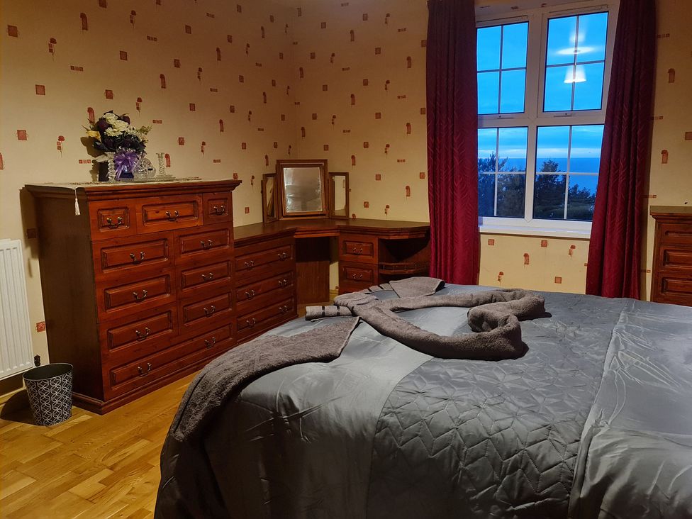 A bedroom with a bed and wooden dresser at Sea View Escape Penmaenmawr