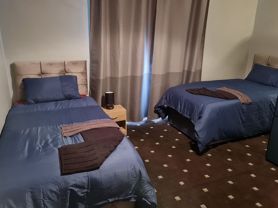 A bedroom with two beds and a bedside table at Sea View Escape in Penmaenmawr