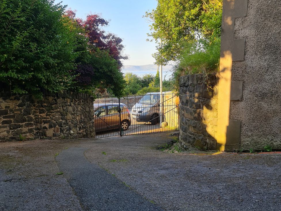 A view of a driveway with vehicles and a gate at Sea View Escape in Penmaenmawr