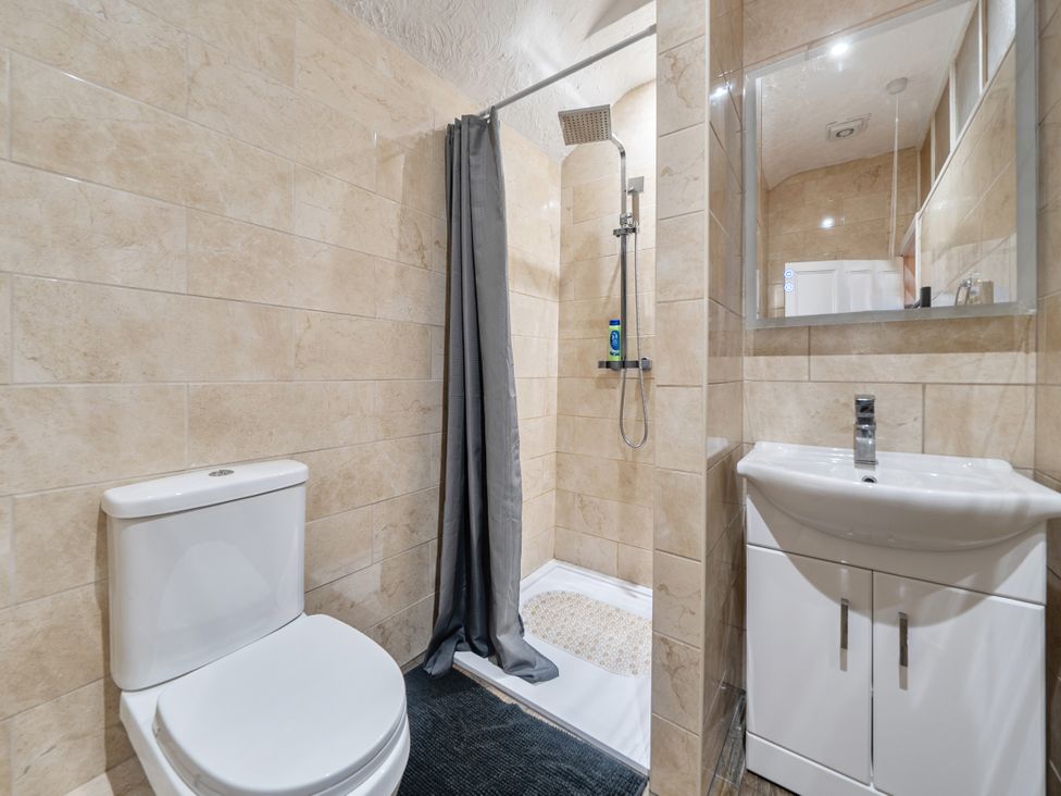 A bathroom featuring a shower, toilet, and sink at Sea View Escape Penmaenmawr