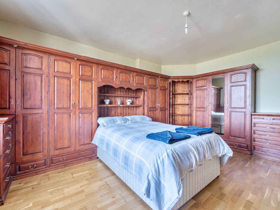 A bedroom with a wooden wardrobe and a bed at Sea View Escape in Penmaenmawr