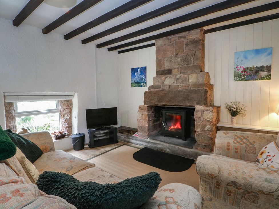 A living room with a fireplace and television at Meadow View Cottage in Matlock