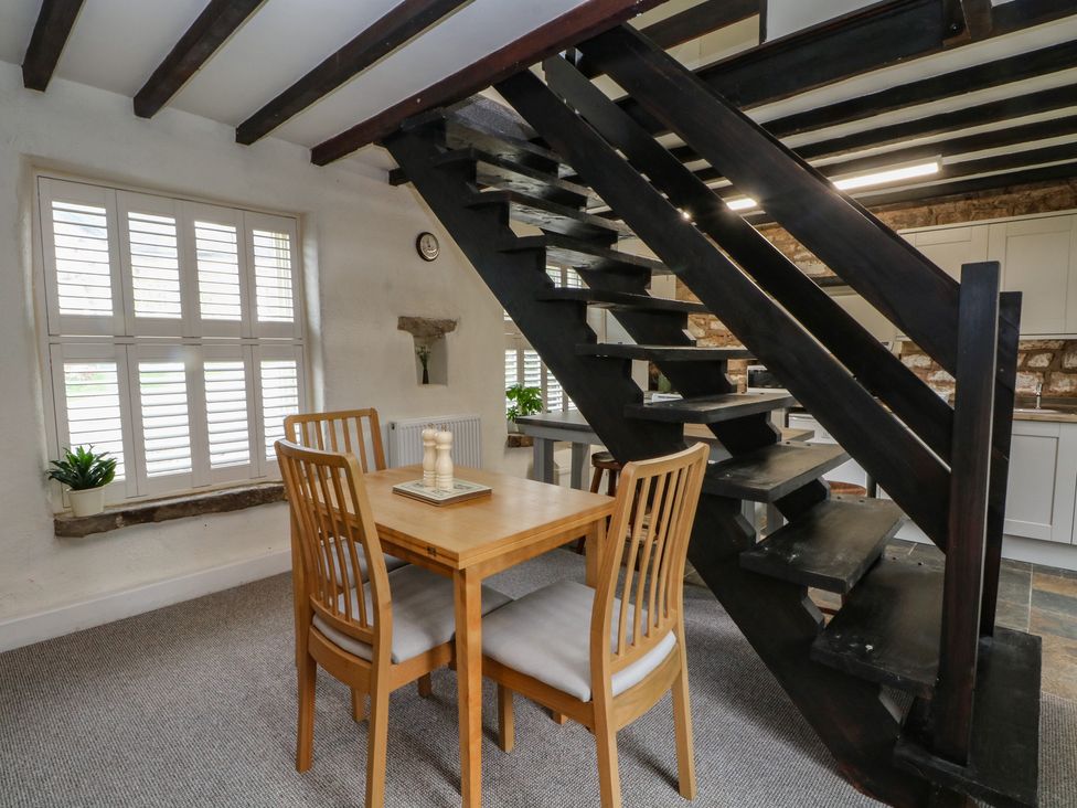 A dining area with a table and chairs near a staircase at Meadow View Cottage in Matlock