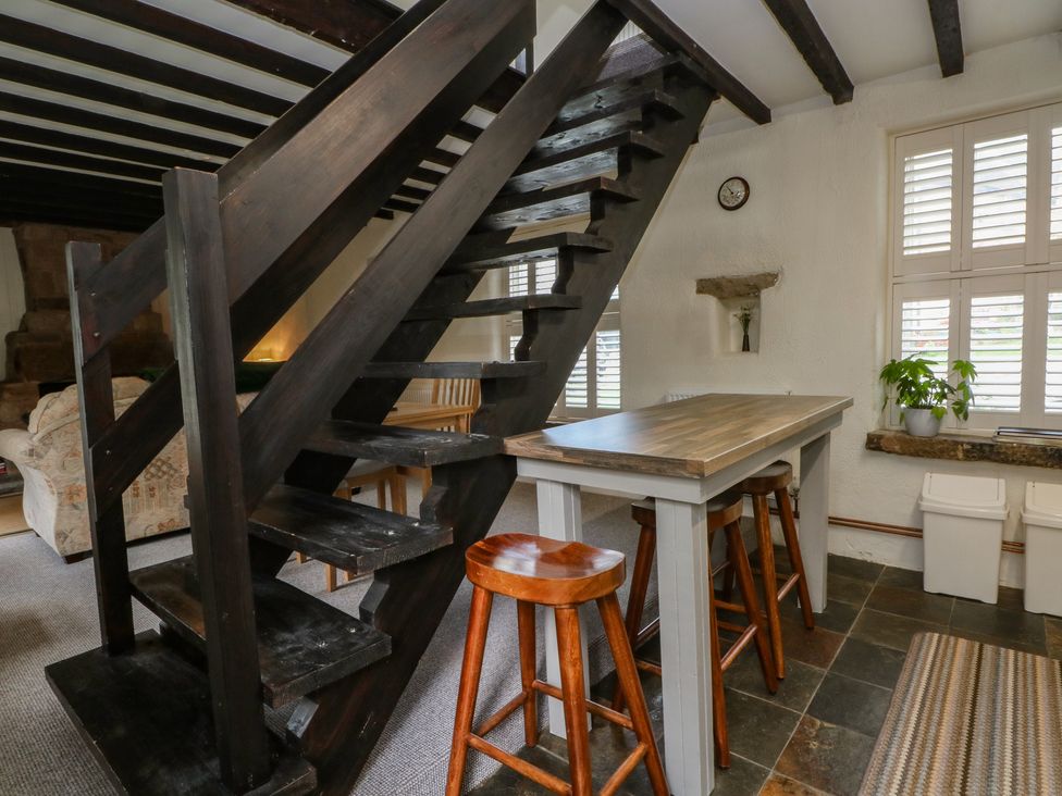 A kitchen with a staircase and bar table at Meadow View Cottage in Matlock