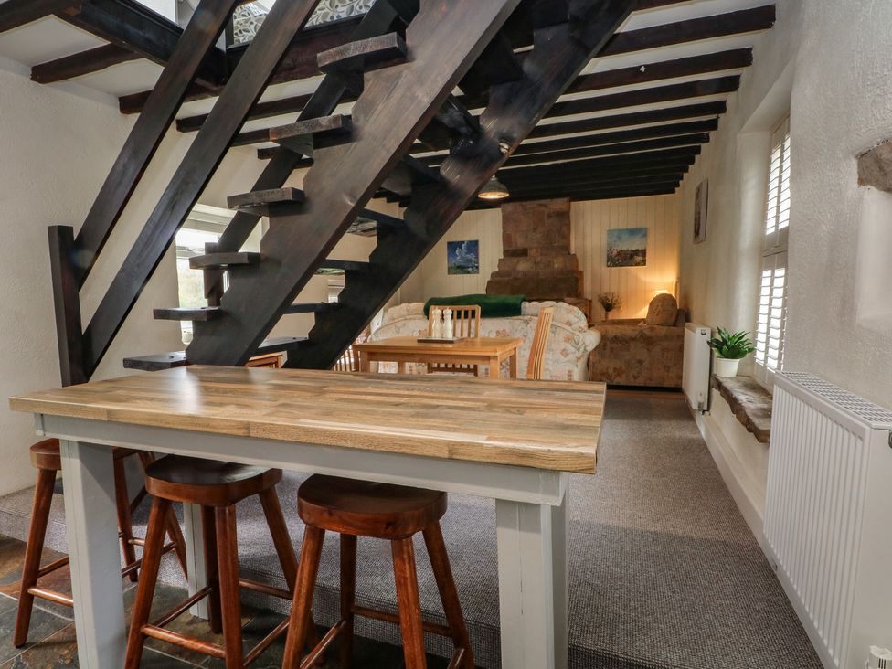 A living room with a staircase and dining area at Meadow View Cottage in Matlock