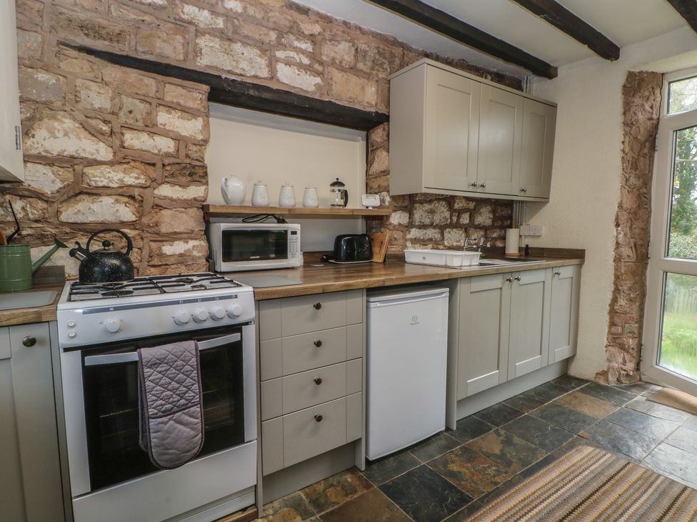 A kitchen with appliances and wooden cabinets at Meadow View Cottage in Matlock