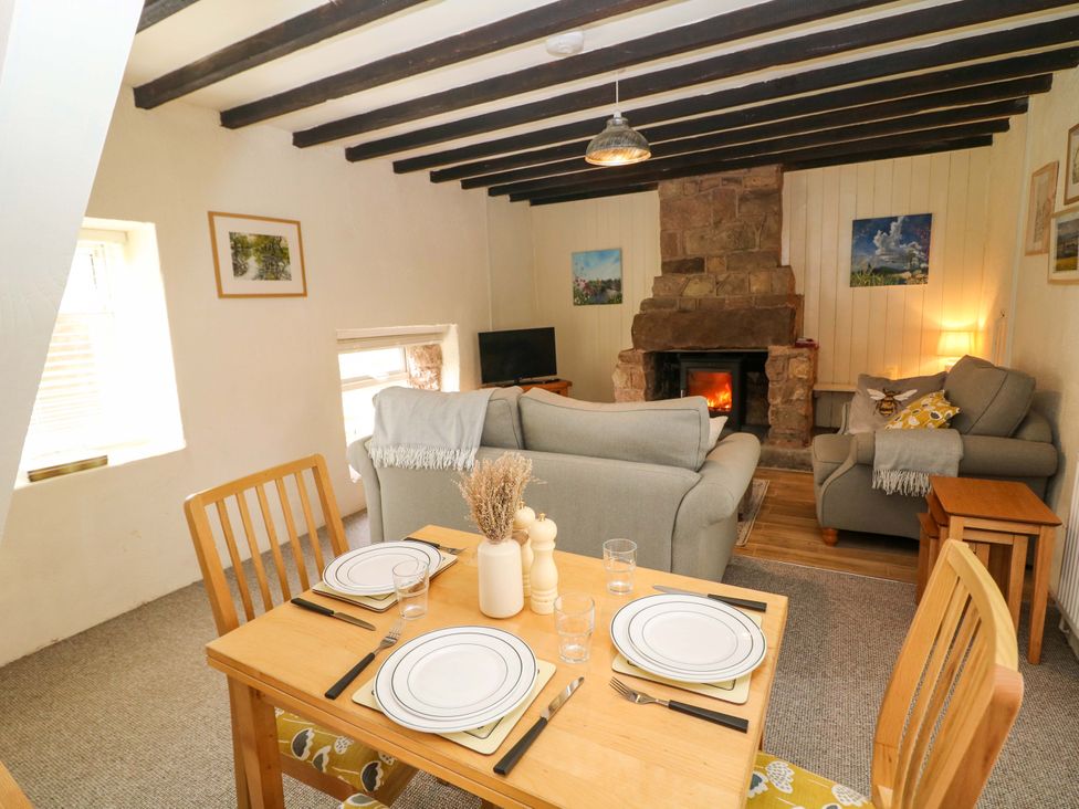 A living room with a fireplace and dining table at Meadow View Cottage Whatstandwell near Crich