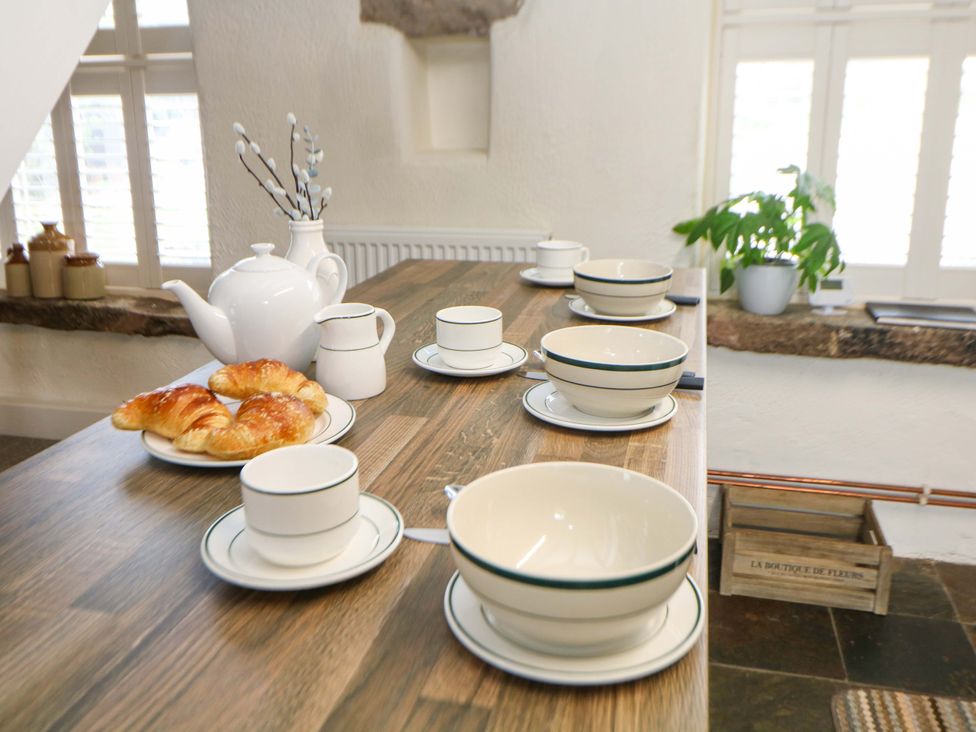 A kitchen table set with cups, bowls, a tea pot, and croissants at Meadow View Cottage in Whatstandwell near Crich