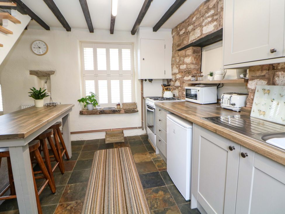 A kitchen with a table and stools at Meadow View Cottage in Whatstandwell near Crich