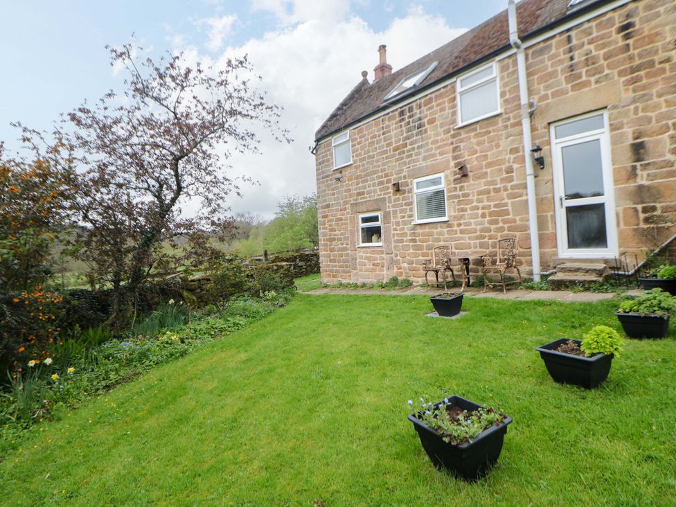 A garden with planters and chairs at Meadow View Cottage in Whatstandwell near Crich