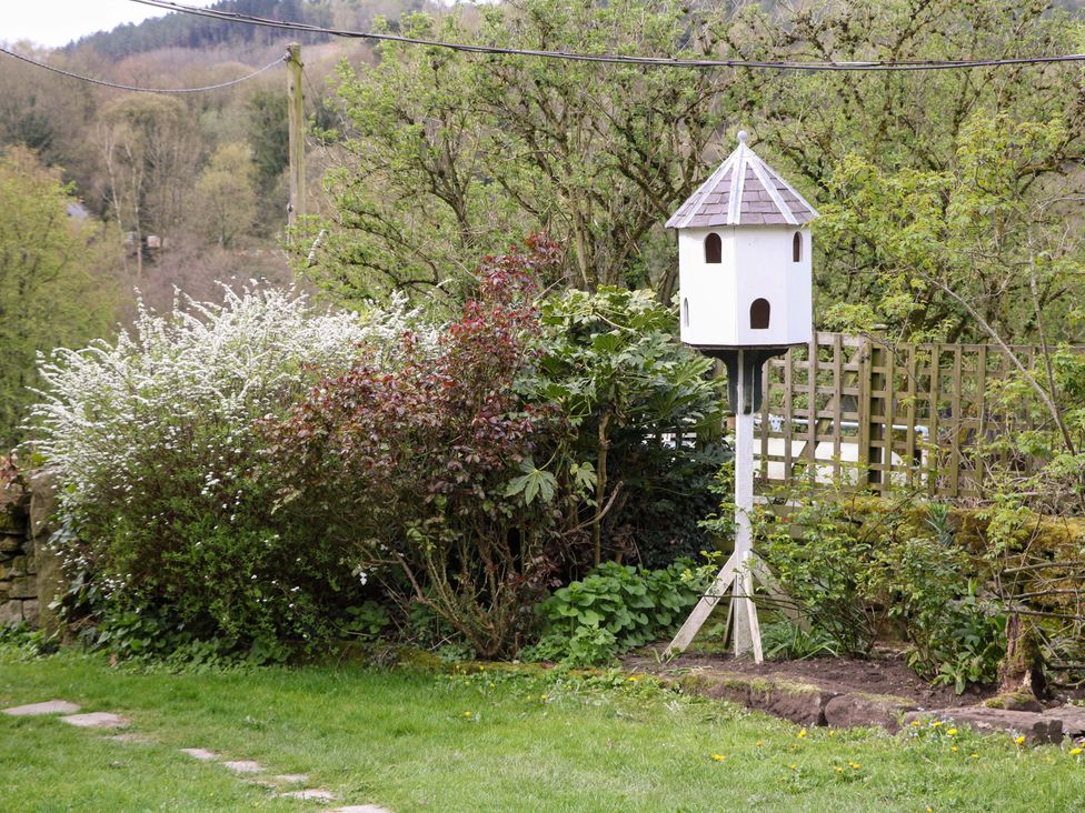 A garden with a birdhouse and bushes at Meadow View Cottage Whatstandwell near Crich