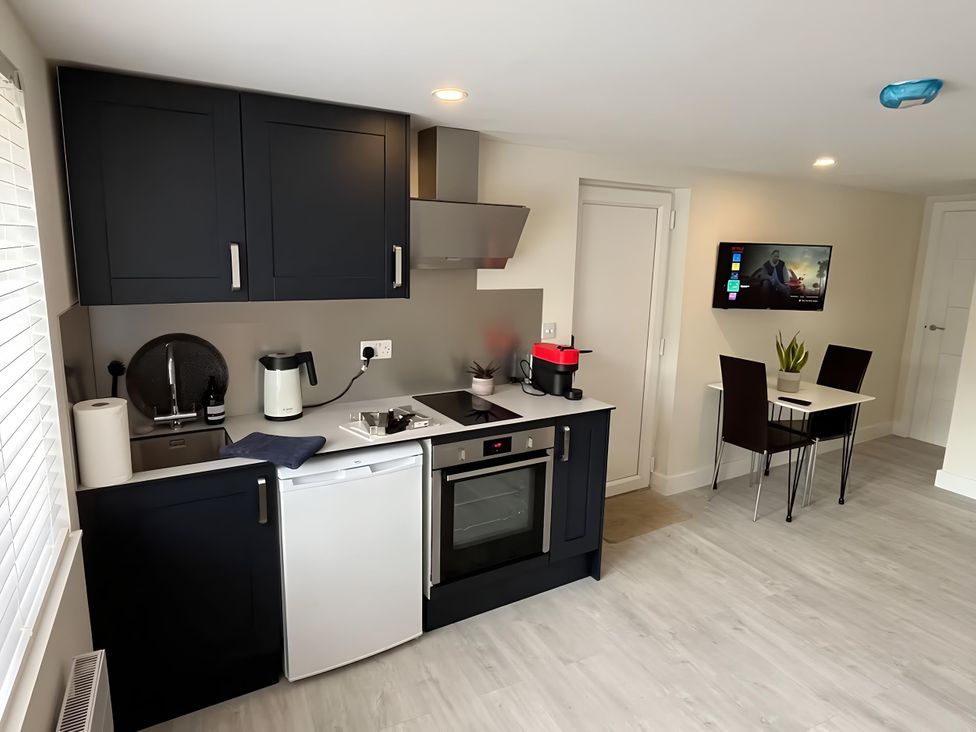 A kitchen with cabinets, sink, stove, refrigerator, and a dining table at River Studio in Warsash