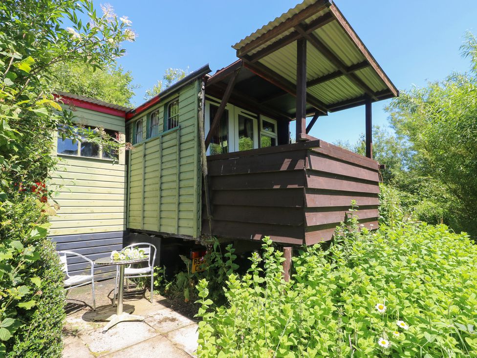 A garden with a building and chairs and table at Rumenco Horse Lorry