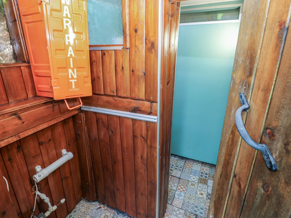 A bathroom with wooden walls and an orange container at Rumenco Horse Lorry