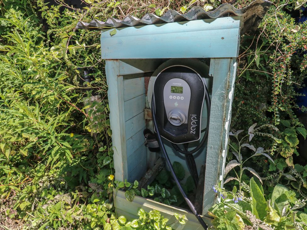 A charging station with cable in a wooden structure surrounded by plants at Rumenco Horse Lorry