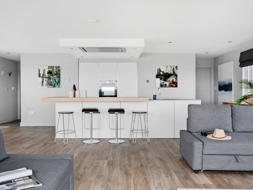 A kitchen with bar stools and a kitchen island at Huxham View and Annex in Stoke Canon