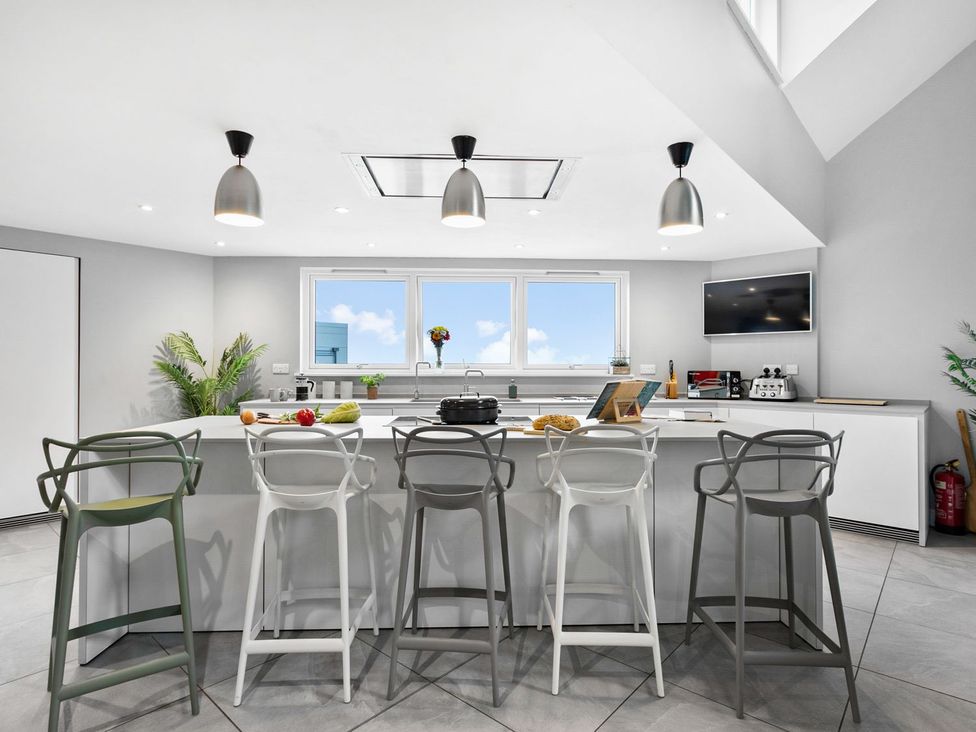 A kitchen with a counter, bar stools, and appliances at Huxham View and Annex Stoke Canon