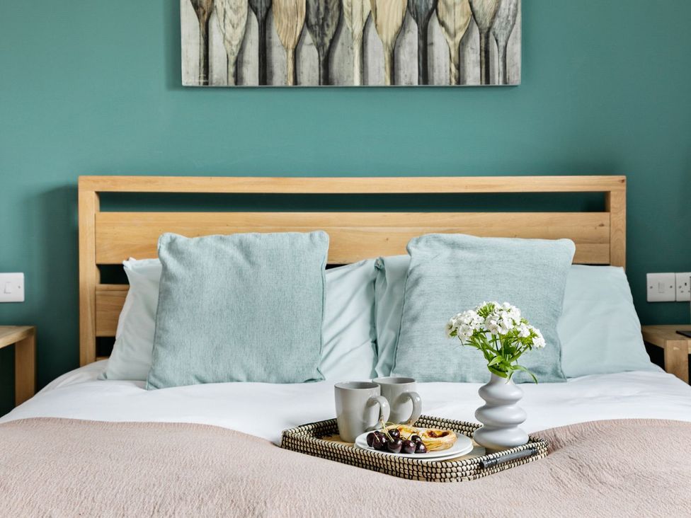 A bedroom with a bed and tray featuring mugs and fruit at Huxham View and Annex in Stoke Canon