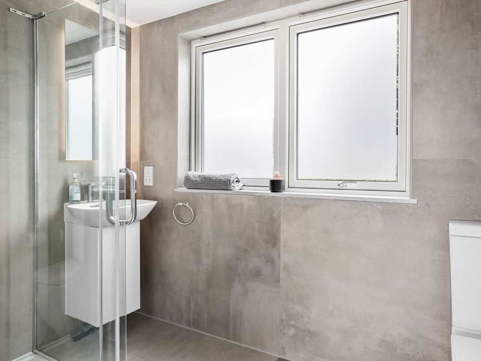 A bathroom with a shower, sink, toilet, and windows at Huxham View and Annex Stoke Canon