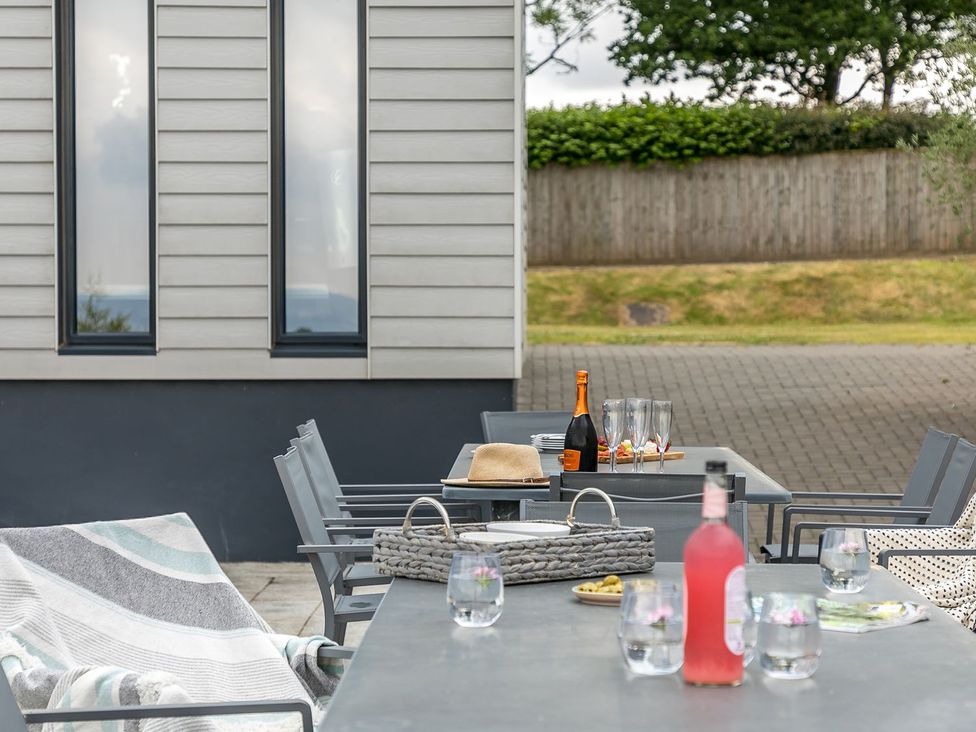 A patio with a table, chairs, and drinks at Huxham View and Annex in Stoke Canon