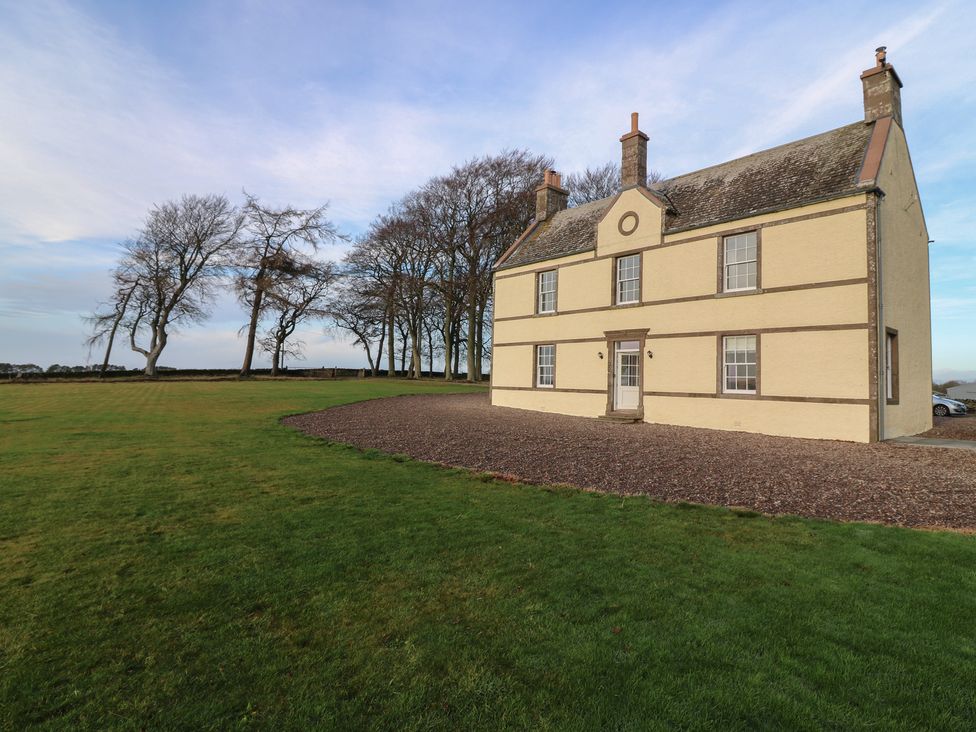 An exterior view of a house surrounded by grass and trees at Balmashanner Farmhouse Forfar