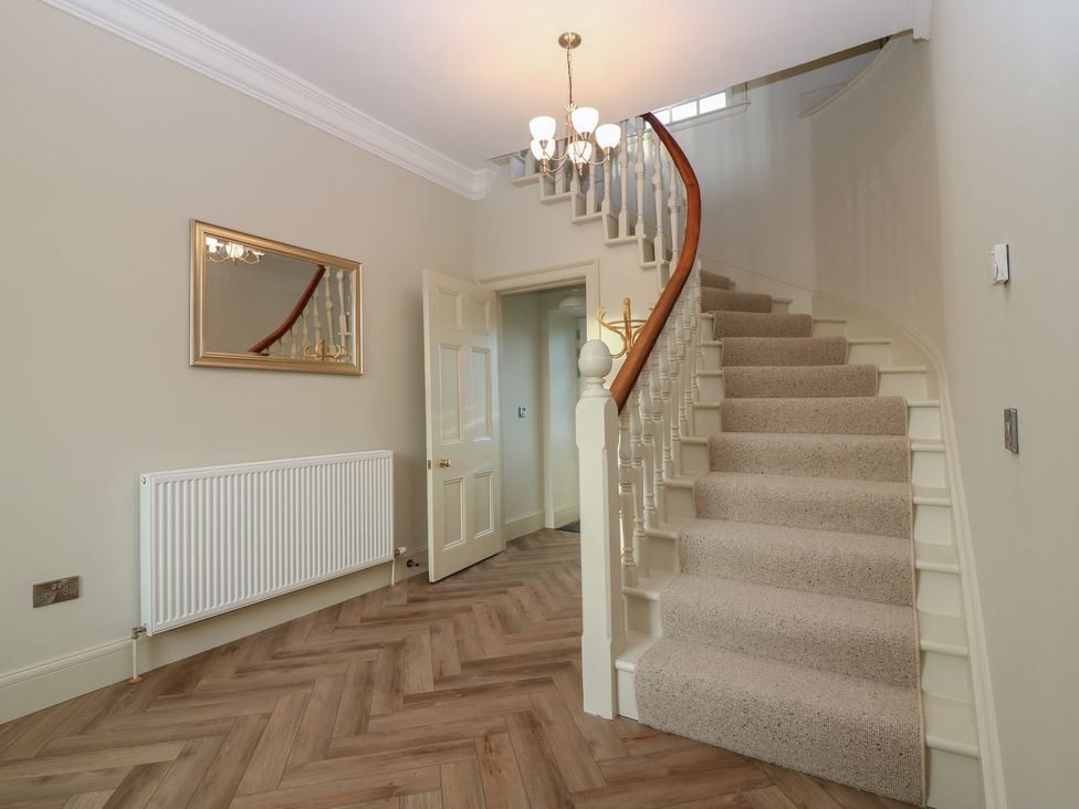 A hallway with a staircase and a mirror at Balmashanner Farmhouse in Forfar