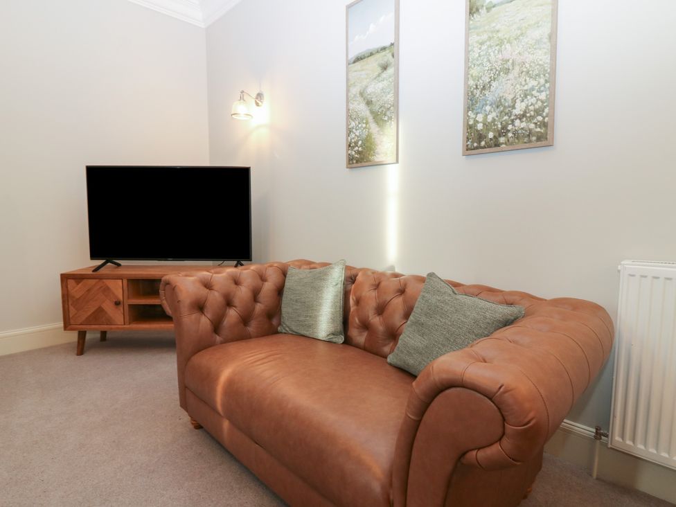 A living room with a sofa and television at Balmashanner Farmhouse in Forfar
