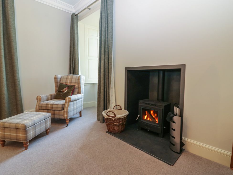 A living room with an armchair and fireplace at Balmashanner Farmhouse in Forfar