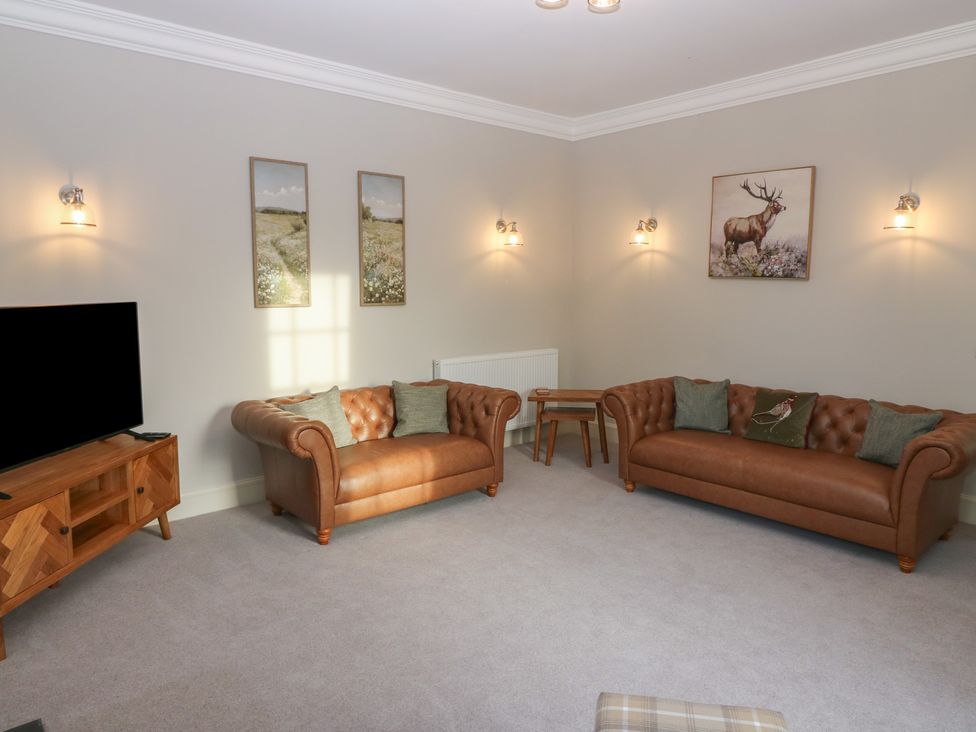 A living room with a tv and sofas at Balmashanner Farmhouse Forfar