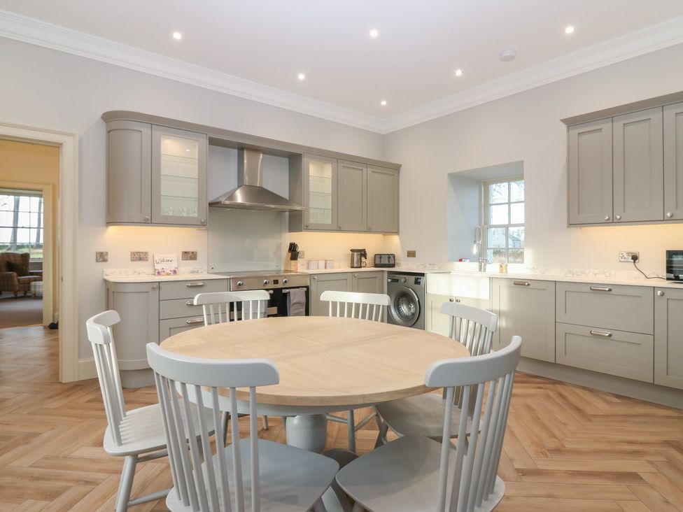 A kitchen with a round table and storage cabinets at Balmashanner Farmhouse in Forfar