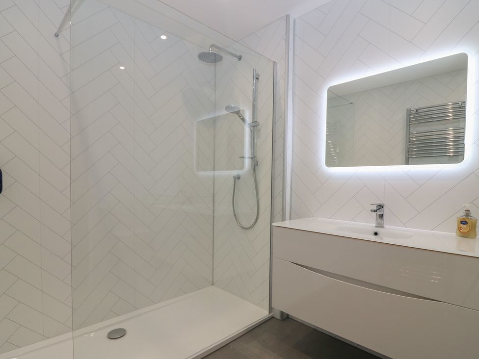 A bathroom with a shower, mirror, and sink at Balmashanner Farmhouse in Forfar